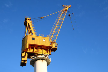  yellow crane in the shipyards of the port in a blue sky