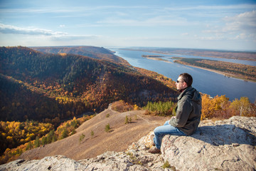 Fototapeta na wymiar a man sits on top of a mountain admiring the scenery