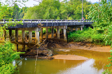 Fototapeta na wymiar Landscape of stone bridge in rural region in Thailand. River after rain and flood