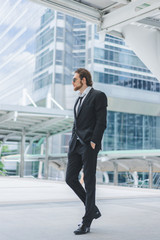 Smart businessman in full suit standing outdoors in cityscape background