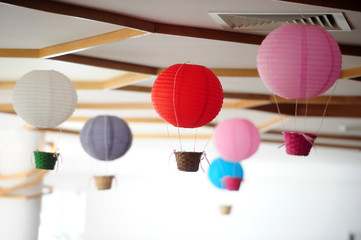 Beautiful colored paper lanterns hanging on the ceiling as air balloons