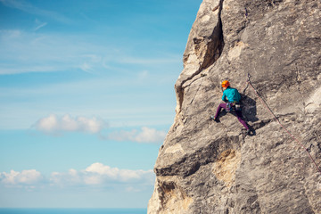 The girl climbs the rock. - obrazy, fototapety, plakaty