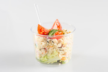 Salad with dressing in plastic container isolated on white background