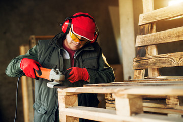 Carpenter working with electric grinder tool in a professional uniform.