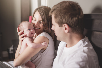 Fototapeta premium Mother father and baby child on a white bed.