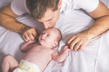 Young father and newborn baby girl on bed at home