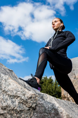 woman stretching legs on rocks