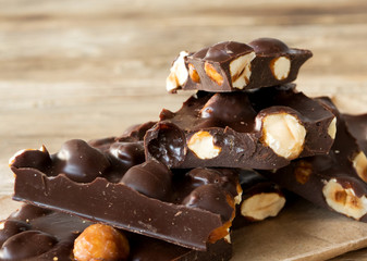 Dark chocolate with whole hazelnuts on wooden rustic background