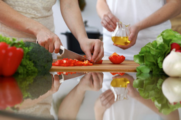 Close-up of  human hands  cooking in a kitchen. Friends having fun while preparing fresh salad. Vegetarian, healthy meal and friendship concept
