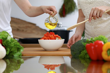 Close-up of  human hands  cooking in a kitchen. Friends having fun while preparing fresh salad. Vegetarian, healthy meal and friendship concept