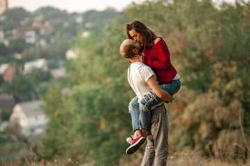 Young man lifted up girl and they kiss on walk in forest.