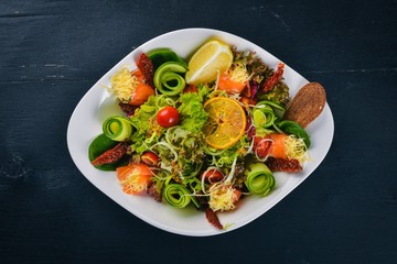 Salad with salted salmon, cheese and salad leaves. On a wooden surface. Top view. Free space for your text.