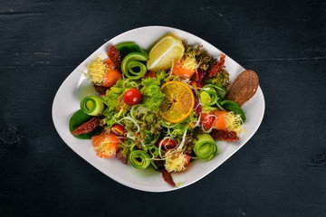 Salad with salted salmon, cheese and salad leaves. On a wooden surface. Top view. Free space for your text.