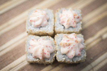 Sushi roll in sesame seeds on a brown background background