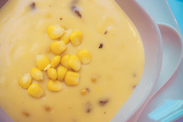 Corn soup and tomato in white bowl on white dish .closeup