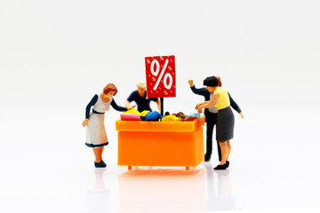 Miniature people: Shoppers buy goods on sale with discount tray.