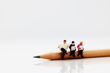 Concept of education and business. Miniature business team sitting on pencil and book use in...