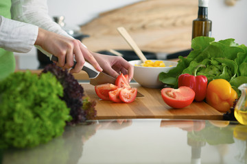Closeup of human hands cooking vegetables salad in kitchen on the glass  table with reflection