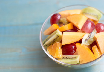 Plate with fruit salad on a blue wooden background