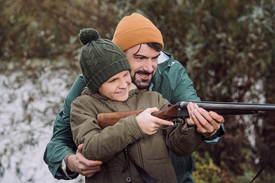 Father helping son aiming with gun