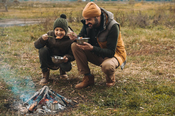 Father and son eating food on nature
