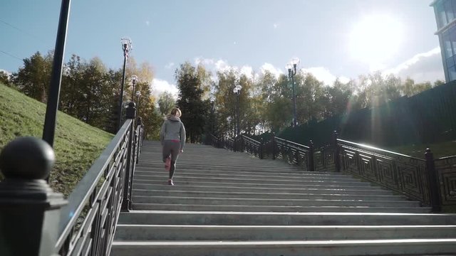 the girl runs up the stairs. The runner runs up the stairs. Slow motion. The camera rises.