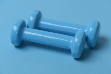 Dumbbells made of blue plastic on blue background