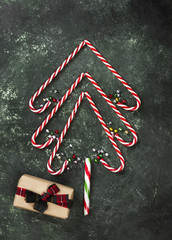 Christmas tree from candy canes and box with gift on a green background. Top view