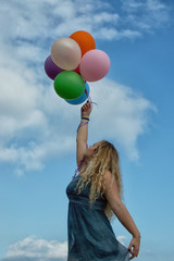 Girl with colorful balloons in front of blue sky