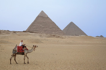 Urlauberin auf einem Kamel alleine in der Wüste vor den Pyramiden