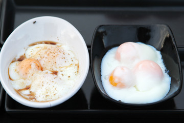 Street food, poached eggs sprinkle pepper in white bowl at market.