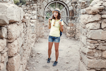 Young female tourist with blue backpack exploring ancient greek town Olympos, near Cirali village in Turkey