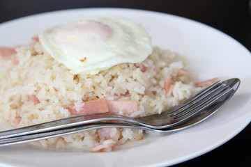 Thai cuisine, fried rice with ham and fried egg on white plate.