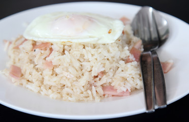 Thai cuisine, fried rice with ham and fried egg on white plate.