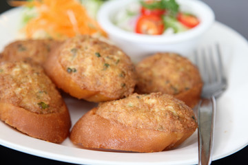 Thai cuisine, fried bread with minced pork spread on white plate.