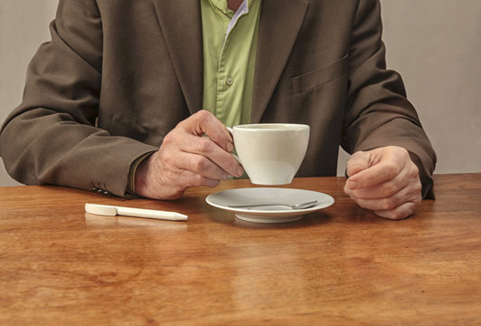 Drinking coffee at desk with pen