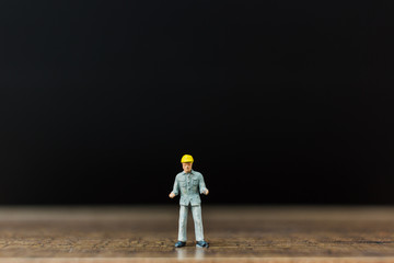 Miniature people worker on wooden floor with black background ,construction concept