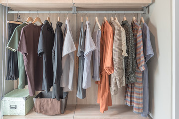 wooden wardrobe with clothes hanging on rail