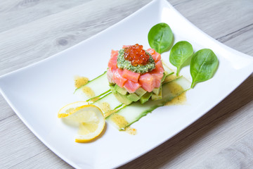 Tartare from salmon, caviar and avocado with pesto sauce and spinach. Close-up, selective focus.