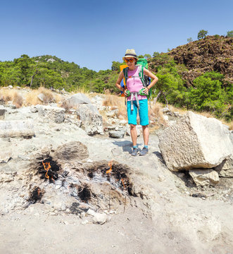 Woman hiker tourist looking at Yanartas chimaera flames in Olympos national park in Turkey