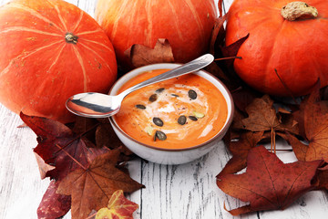 Roasted pumpkin and carrot soup with cream and pumpkin seeds on wooden background