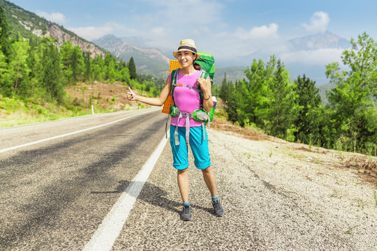 Happy Girl with hat and backpack hitchhiking on the road in Turkey, lycian way