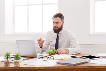 Fototapeta premium Busy man has business lunch in modern office interior