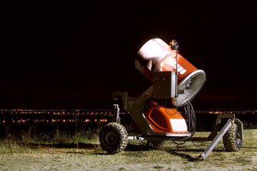 Snow cannon - Snowmaking system in the ski resort - red high-tech system, sprinkling snow of red color, stands at night on the ski-run