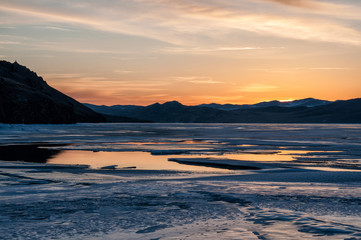 ice and water near the mountain on the frozen Lake Baikal before sunrise