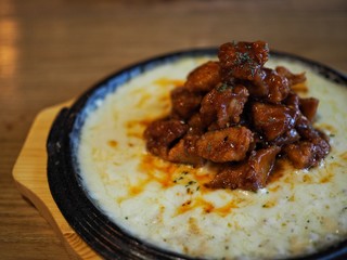 cheese korea chicken in black pan with side dish on wood table top view
