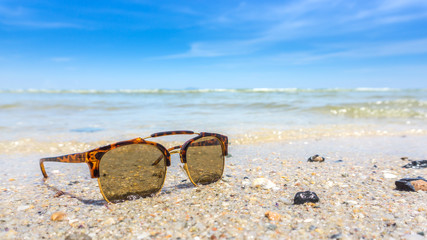 leopard sunglasses on the beach with blue sky background