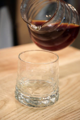 Barista pours a coffin into the glass cup. He serves a drink.