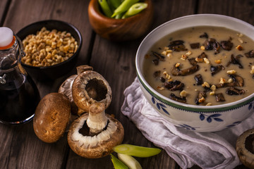 mushroom soup shot at an angle on wood boards with loose mushrooms scallions hazelnuts landscape