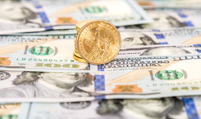 One dollar coins lying over paper currency banknotes close up